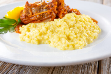 A view of a plate featuring creamy risotto next to osso buco.