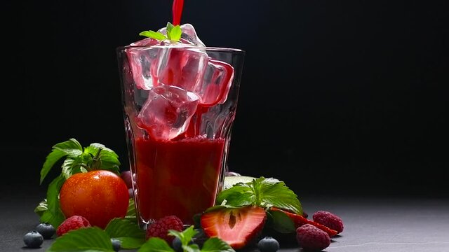 Mixed berry and beetroot pouring into tall glass with surrounding fruits