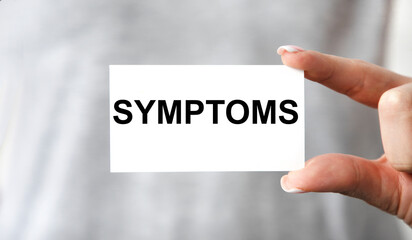 The girl holds a card with the text symptoms. A medical concept.