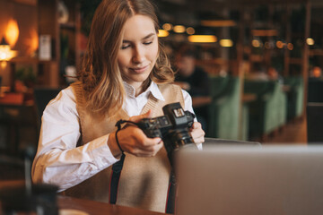 Young woman photographer working with her camera with laptop in a cafe