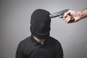 Person with a handgun aiming on a man head.