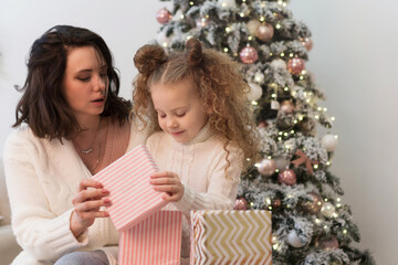 Fototapeta na wymiar Family christmas morning. Mom and daughter open gifts. Girls greet Christmas among boxes of gifts and Christmas lights.