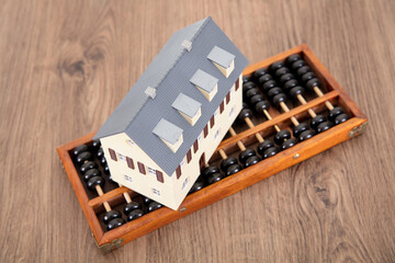 A traditional calculation tool abacus and a small house model on the table