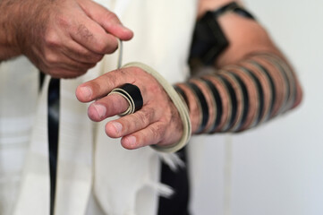 Jewish man wrapping himself with with Tefillin