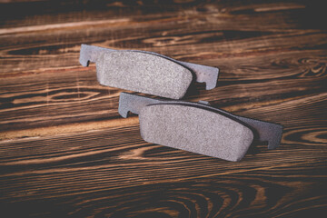 Studio photo of new car brake pads on a wooden background.