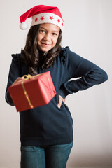 Vertical photography of little girl wearing a santa hat and holding a present.