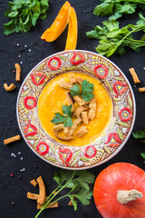 Delicious healthy pumpkin soup, herbs, and ingredients for the dish. Creative atmospheric decoration