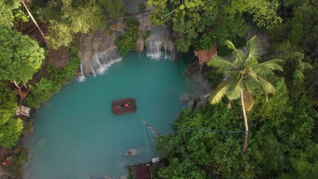 Drone shot side ways shot of a girl thats laying on a bamboo raft at the Cambugahay Falls Siquijor Island Cinematic Drone Aerial in 4K