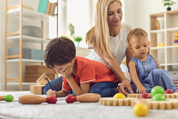 Obraz premium Mother and children playing and drawing at home together
