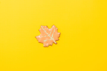 Sweet homemade leaf cookie with icing isolated on yellow background minimal flat lay composition.