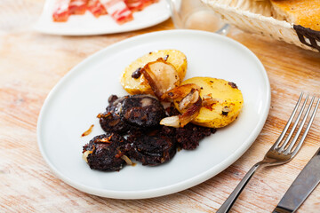 Fried morcilla (blood sausage with rice) served with side dish of baked potatoes