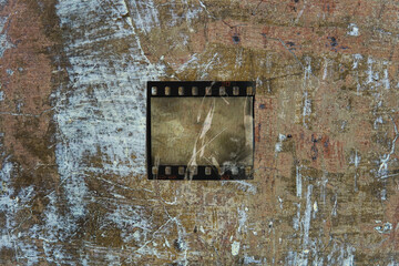 single 35mm filmstrip with transparent sticker tape all over the frame cell lying on grungy stone background.