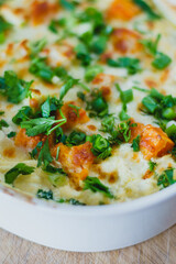 Top view of a traditional pumpkin pie with turkey and baked vegetables in a white dish on a wooden board.