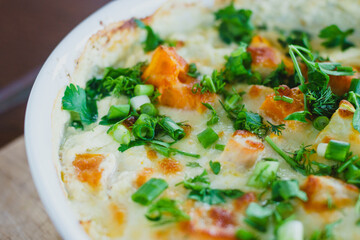 Top view of a traditional pumpkin pie with turkey and baked vegetables in a white dish on a wooden...