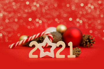 Horizontal Christmas card with 2021 numbers in the foreground and New Years balls, pine cones and bokeh on a red background. New Year's layout, Side view. Copyspace