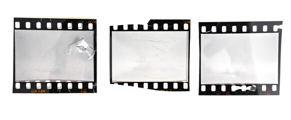 three damaged 35mm filmstrips or snips with empty frames on white background, grungy looking film...