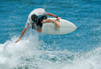 A surfer flies above the wave as he executes a radical aerial move.