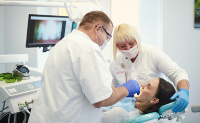 Obraz premium Doctor dentist treats teeth of a beautiful young girl patient. The girl on reception at the dentist. Doctor dentist treats tooth