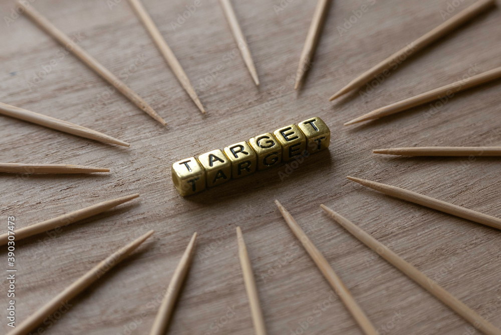 Poster concept of target. selective focus of sharp wood pointing to gold alphabet beads of word target on w
