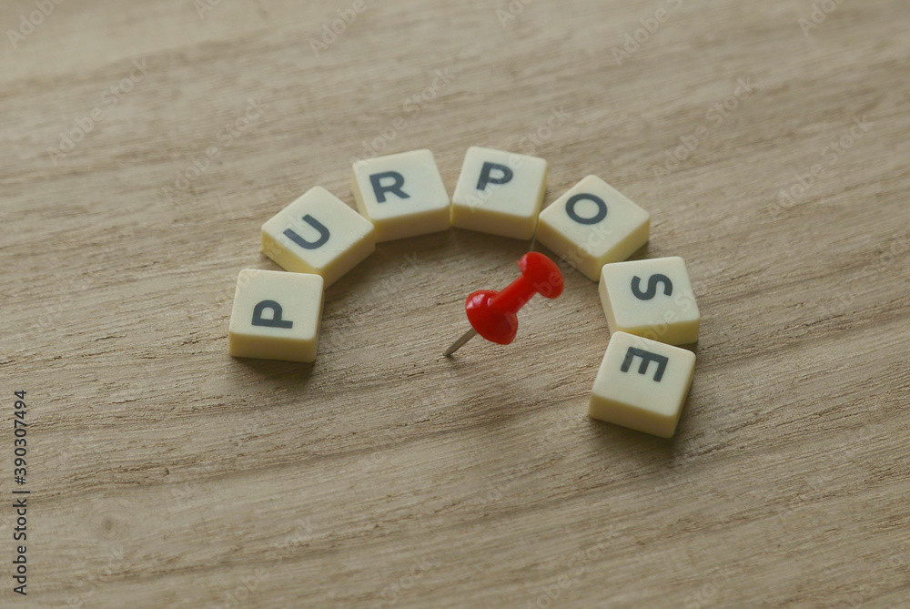 Poster selective focus of alphabet of word purpose with red push pin on wooden background.