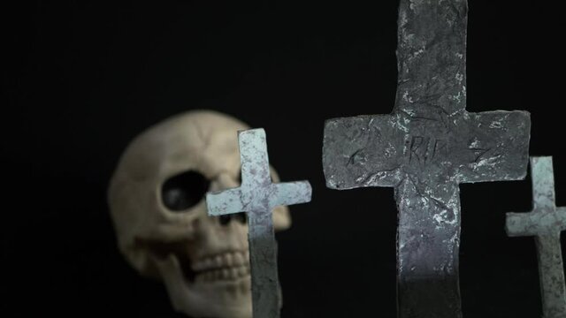 Human skull surrounded my graveyard crosses panning shot