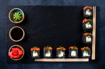 Traditional Japanese food - sushi, rolls and chopsticks for sushi on a dark background. Top view