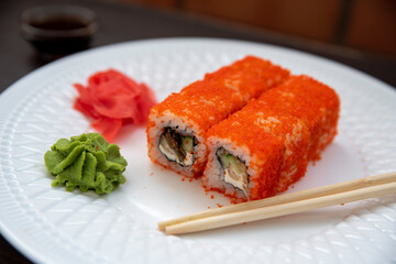 Set of eight sushi rolls on a white plate with salmon, eel, tuna, avocado, king prawn, cream cheese, tobiko caviar, Chuka. The sushi menu. Japanese cuisine. Top view of assorted sushi.