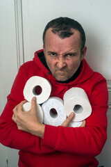 Portrait of angry man with many paper toilet rolls in hands