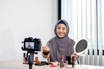 Muslim women making video beauty vlogger bloggers doing a cosmetic makeup tutorial vlog with brushes looking camera Save clips and share them on social media live via the internet Online