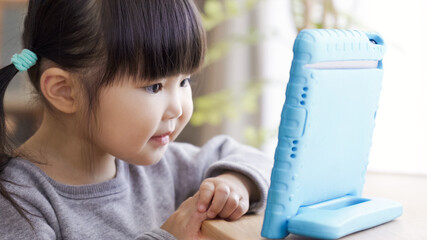 リビングでタブレットを見る子供