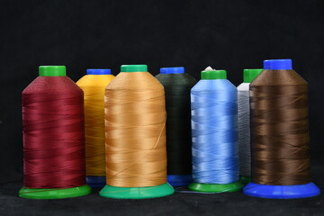 Set of colored threads for sewing on coils. Pile of big colorful spools of thread. Colored thread spools of thread large class, textiles, background