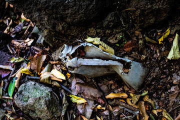 Old white plastic bottle buried in the ground.