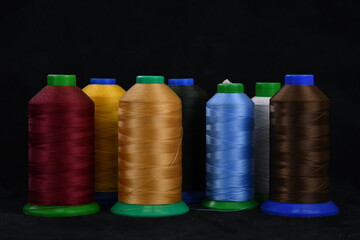 Set of colored threads for sewing on coils. Pile of big colorful spools of thread. Colored thread spools of thread large class, textiles, background