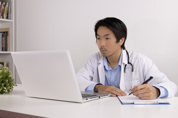 Young Asian Doctor Man in Lab Coat or Gown with Stethoscope Writing Experimental Results Report and...