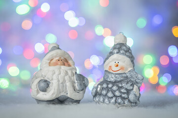 Christmas greeting card with decorative cute snowman and Santa Claus. Bokeh effect on background