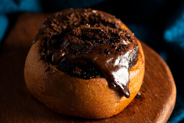 Fresh baked chocolate scroll pastry with melting chocolate, food background.
