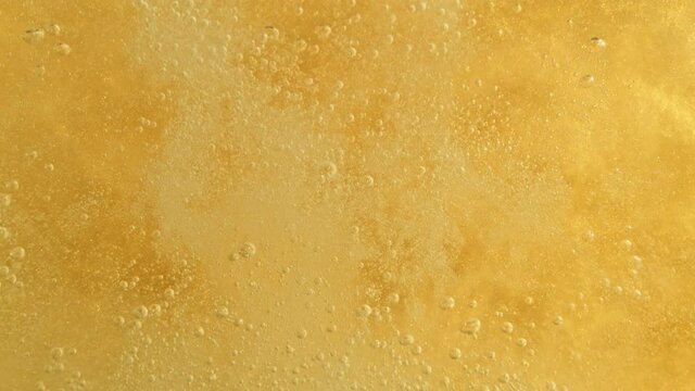 Super Slow Motion Detail Shot of Champagne Bubbles on Golden Luxury Background at 1000fps.