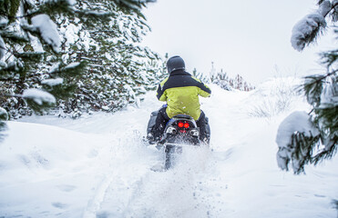 Man is riding snowmobile in mountains. Pilot on a sports snowmobile in a mountain forest. Athlete rides a snowmobile in the mountains. Snowmobile in snow. Concept winter sports © Yevhen