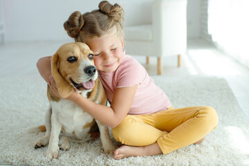 Happy child with a dog. Portrait of a girl with a pet. Beagle licks with a teenager. High quality photo.