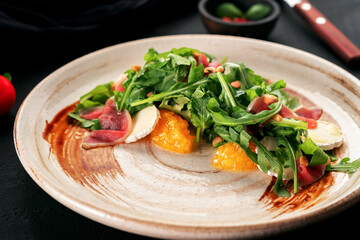 Fresh salad with arugula, Parma ham and soft cheese on a plate, Italian cuisine
