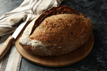 Towel, board with bread and knife on black smokey background