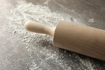 Rolling pin and flour on gray background