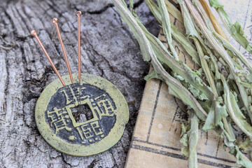 Acupuncture needles on an ancient chinese bronze coin and an old medical book and herbs