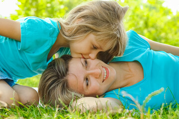 child with mother play outdoors in a park on the mother in the grass