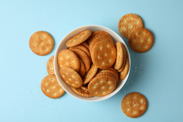 Bowl with tasty cracker biscuits on blue background