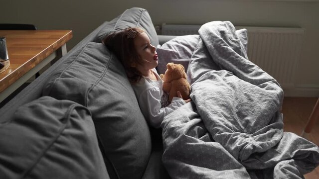 toddler child at home on the couch in living room. Runny nose, flu season. Cold weather, indoors heating 