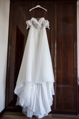 bride's wedding dress hanging on the wardrobe