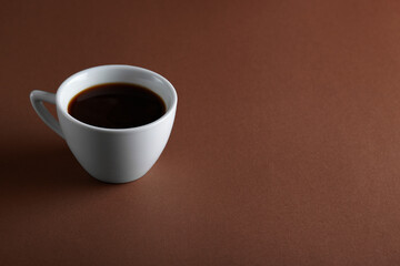 Coffee cup on brown background. Cup of black coffee with copy space.