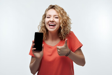 Young laughing woman Showing Smartphone Blank Screen, looking at Camera Recommending Mobile App