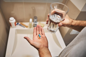 Man taking daily dosage of pills with water